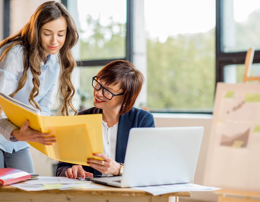 mulheres-de-negocios-jovens-e-mais-velhas-trabalhando-juntas-em-documentos-no-interior-de-um-escritorio-moderno (1)